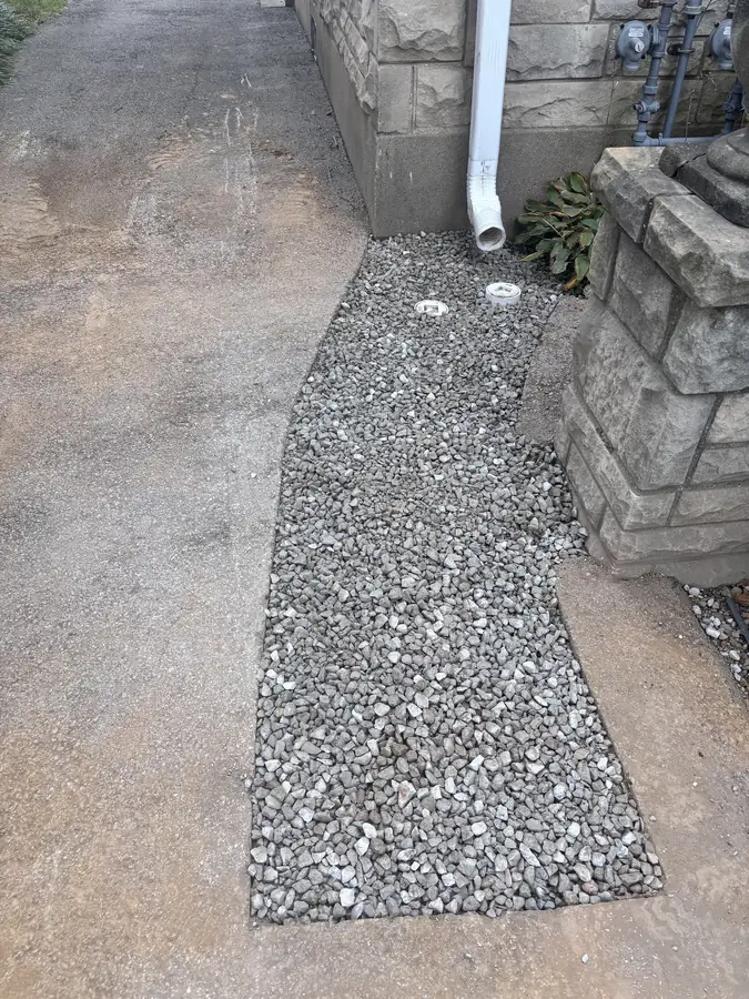 Trench filled with gravel along a walkway after the line was replaced