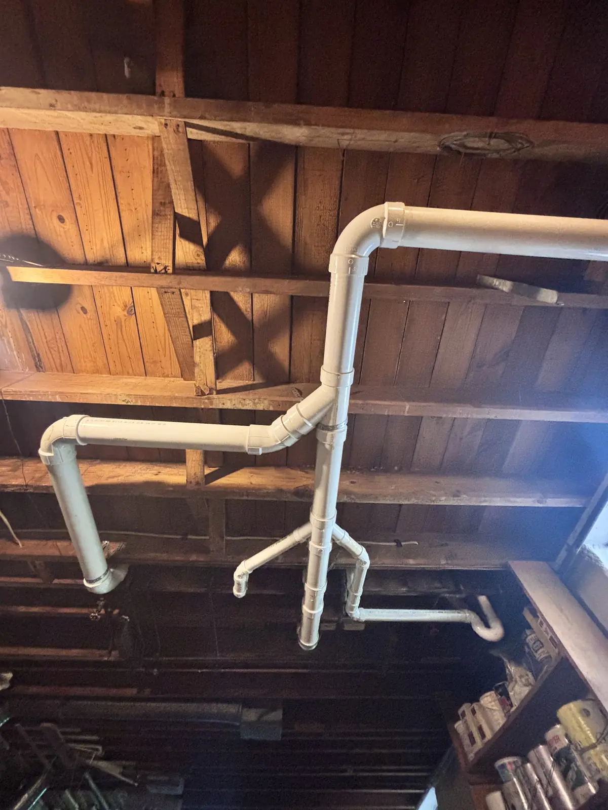 New PVC drain line hung along wood joists
